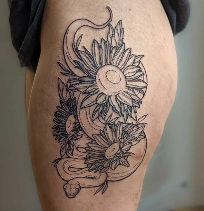 Snake tattoo intertwined with flowers, elegantly inked on skin.