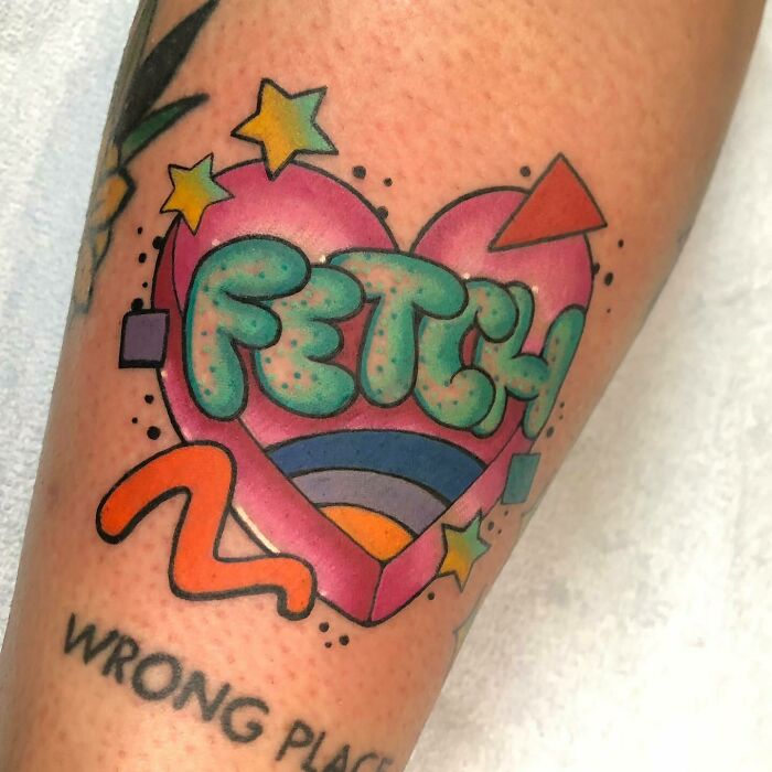 90s tattoo featuring a colorful heart with the word "FETCH" and geometric shapes.