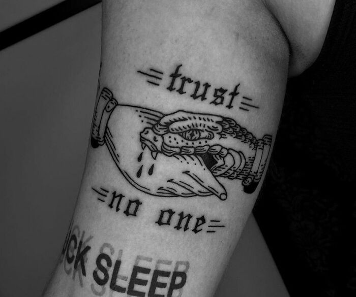 Gothic tattoo of a snake biting a hand with "trust no one" text.