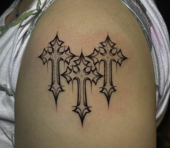 Gothic tattoo featuring three ornate crosses in black ink on an arm.