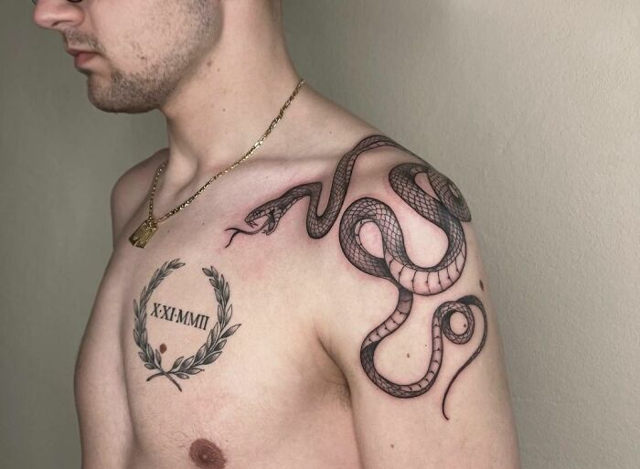 Man with an intricate snake tattoo across his shoulder and chest.