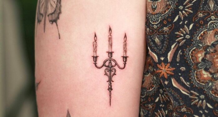 Gothic tattoo design of a detailed candelabrum with three lit candles on an arm.