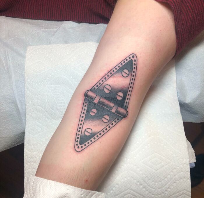 Elbow tattoo featuring a detailed hinge design on a person's arm.