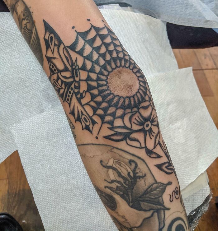 "Intricate geometric and floral elbow tattoo design, showcasing bold black ink detailing."
