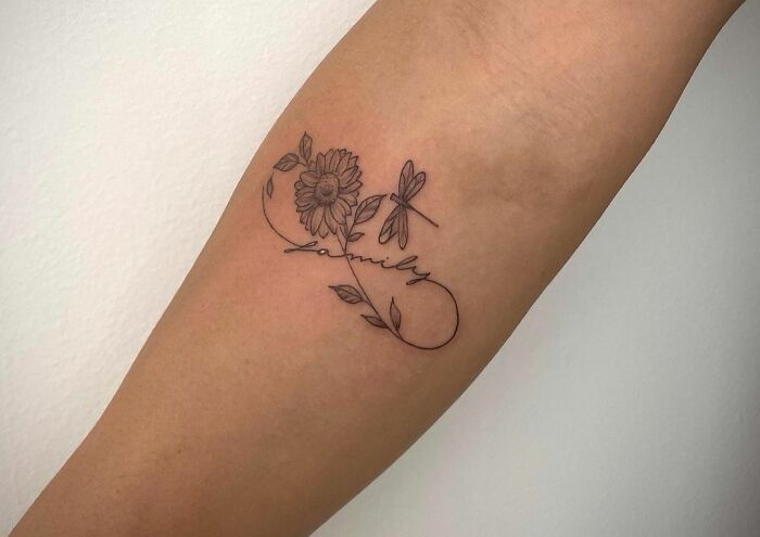 Infinity tattoo with flowers and the word "family" on an arm, symbolizing eternal creativity.