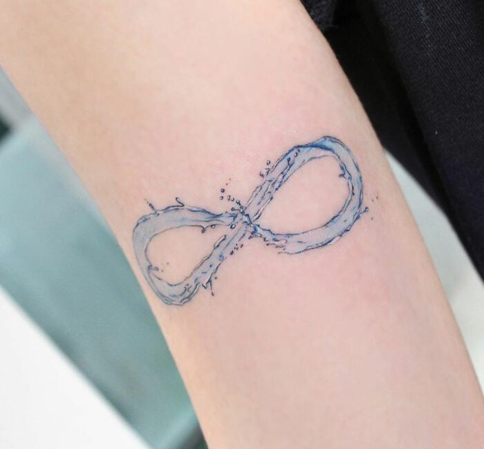 Water-inspired infinity tattoo symbolizing eternal creativity on a person's forearm.