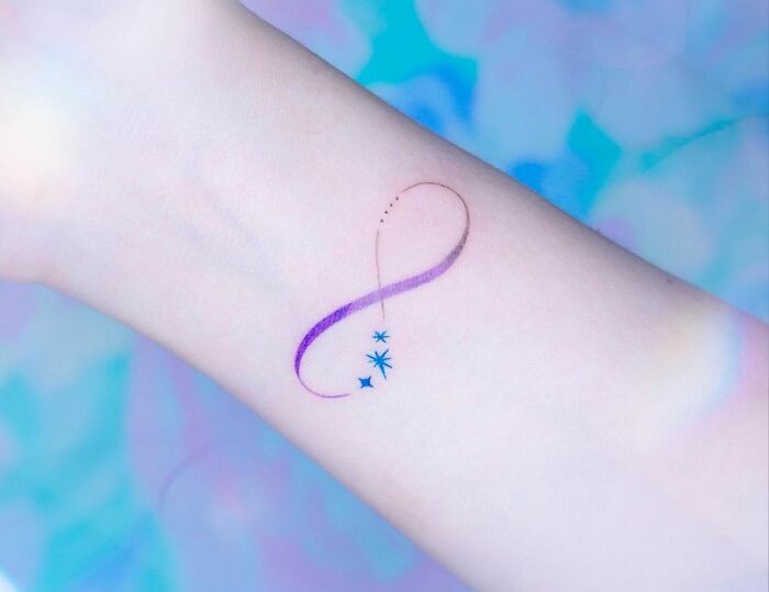 Abstract infinity tattoo with stars on wrist, showcasing eternal creativity.