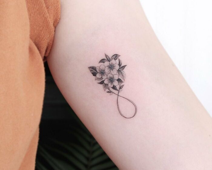 Floral infinity tattoo on arm, showcasing eternal creativity and style.