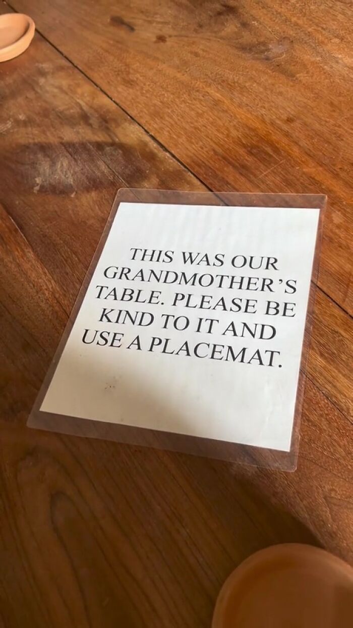 Note on wooden table in Airbnb showing rules asking guests to be kind and use a placemat on grandmother&rsquo;s table.