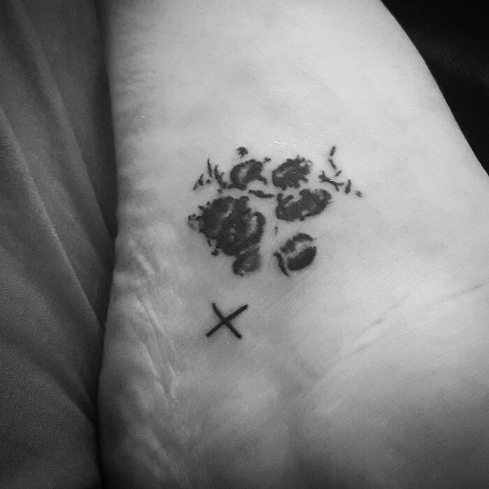 Paw print memorial tattoo on foot, honoring family with love and remembrance.