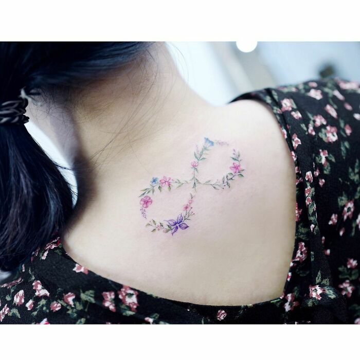Floral infinity tattoo on neck, symbolizing eternal creativity, with colorful flowers intertwined on a floral dress.
