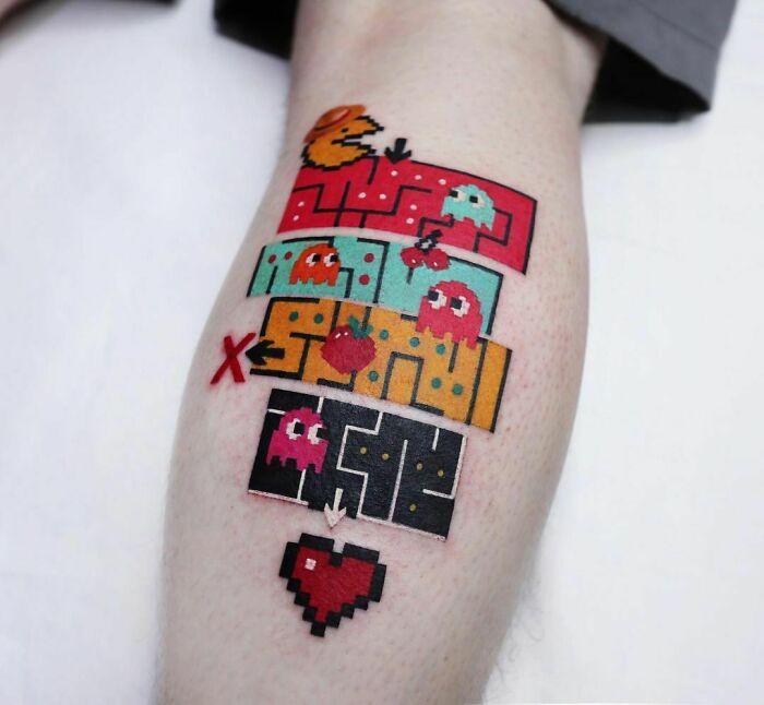 Pixelated Pac-Man video game tattoo featuring Pac-Man and ghosts on a person's leg.