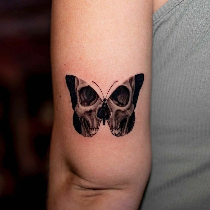Butterfly and skull design elbow tattoo on arm combines elegance with edginess.