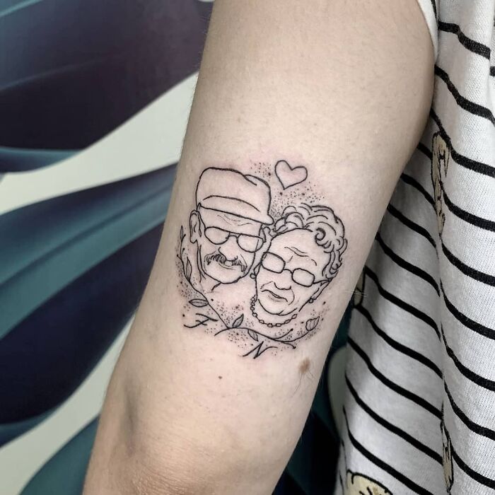 Memorial tattoo on arm featuring an elderly couple's portrait with a heart, symbolizing family honor.