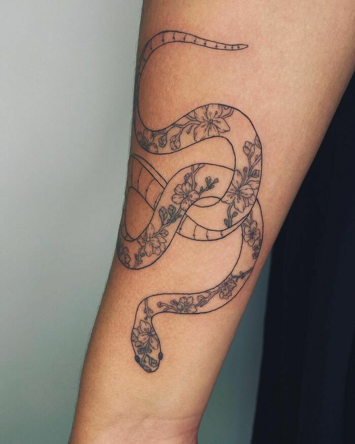 Floral snake tattoo design on forearm with intricate details and patterns.