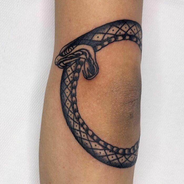 Snake design elbow tattoo in black ink, showcasing a unique ouroboros pattern.