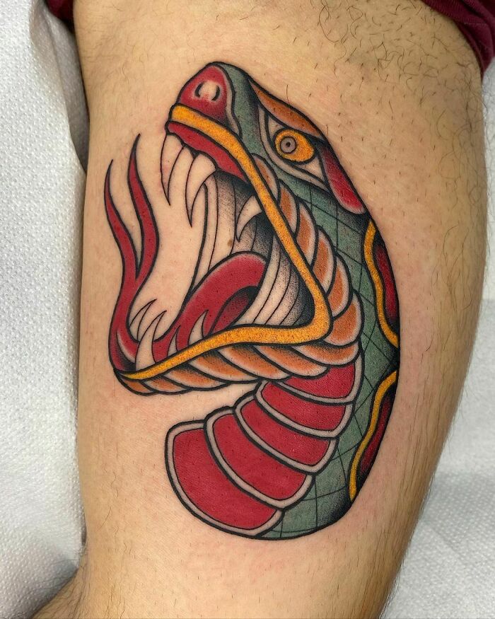 Close-up of a vibrant snake tattoo design on a leg, showcasing intricate patterns and bold colors.