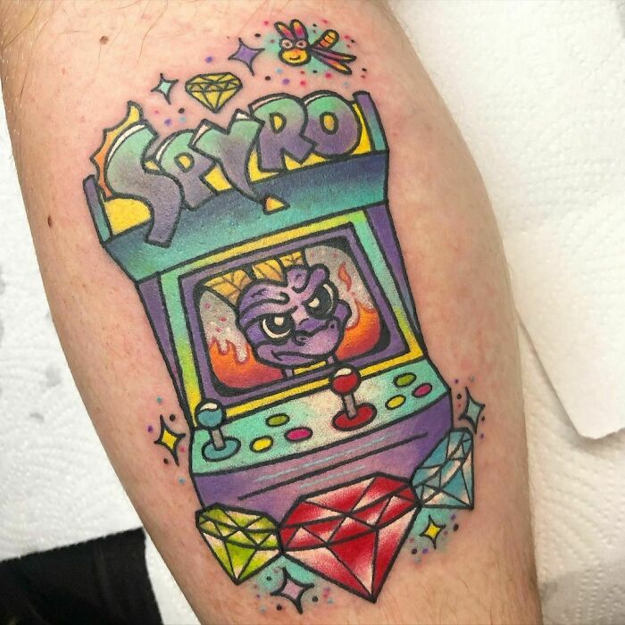 Colorful video game tattoo featuring Spyro, arcade design with gems, perfect for hardcore gamers.