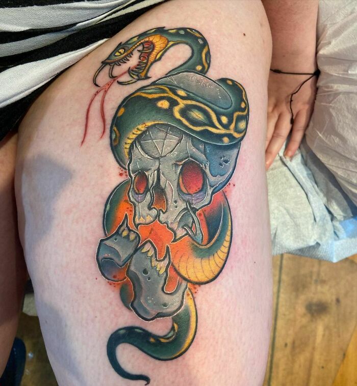 Colorful snake tattoo wrapped around a skull with vivid shading on skin.