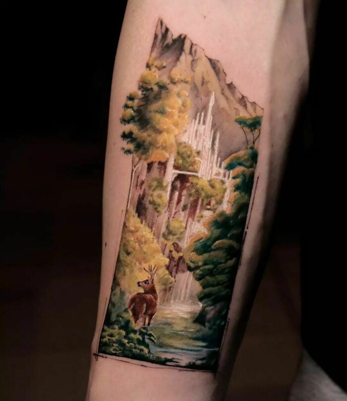 Colorful Lord of the Rings tattoo depicting a serene forest scene with a deer and tall trees on an arm.