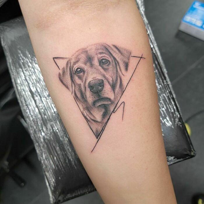 Dog memorial tattoo on arm with geometric design.