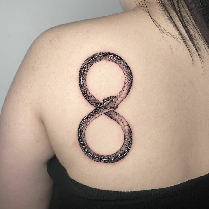Snake infinity tattoo on a person's back, symbolizing eternal creativity.