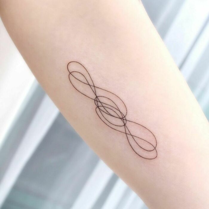 Minimalist infinity tattoo design on forearm, showcasing eternal creativity through intricate overlapping loops.