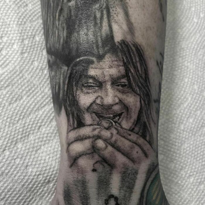 Black and gray Lord of the Rings tattoo of a character holding a ring, detailed portrait on forearm.
