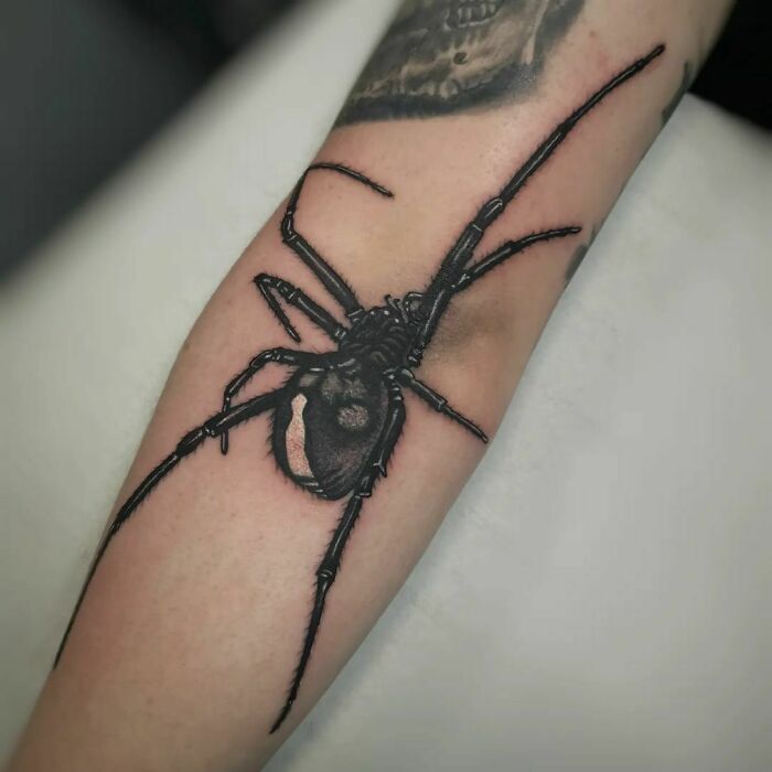 Realistic black spider tattoo on an elbow, showcasing unique tattoo artistry.