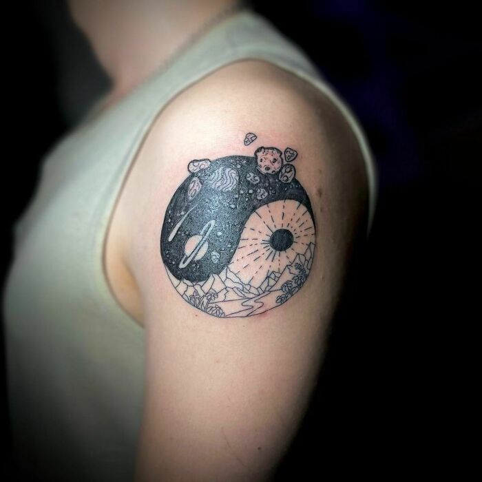Yin Yang tattoo on arm, featuring cosmic and nature patterns, symbolizing life's duality.