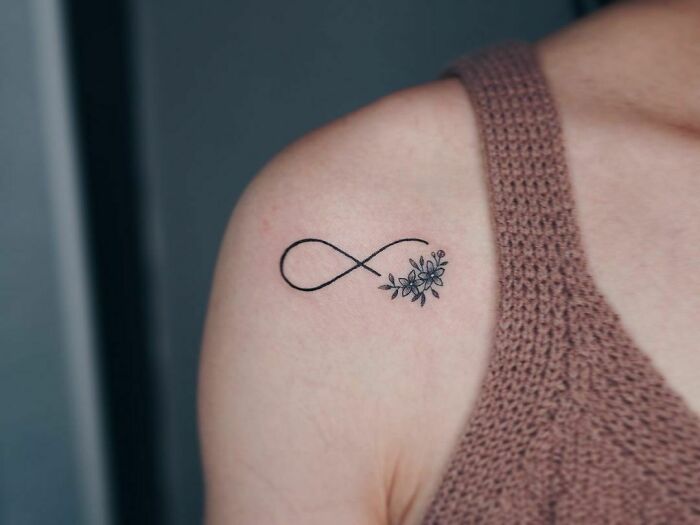 Infinity tattoo with floral design on shoulder, symbolizing eternal creativity.