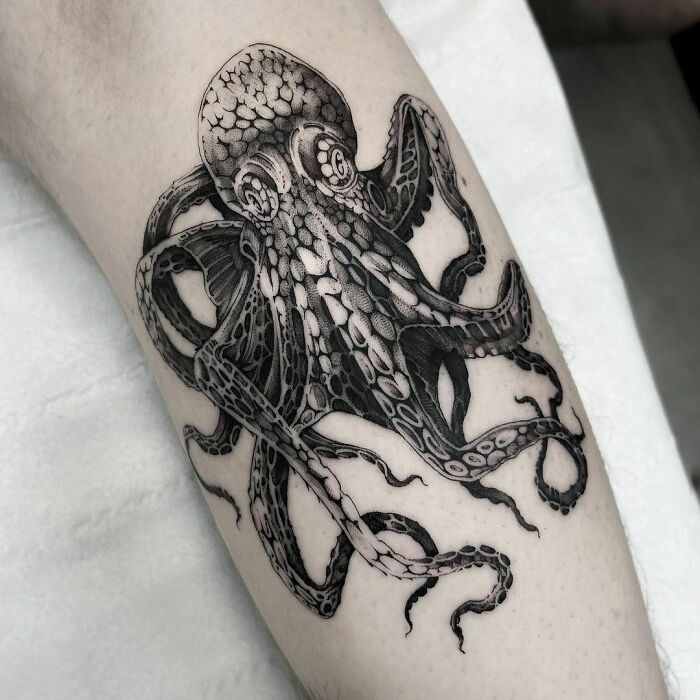 Black and grey octopus tattoo on arm, showcasing intricate and gothic design elements.