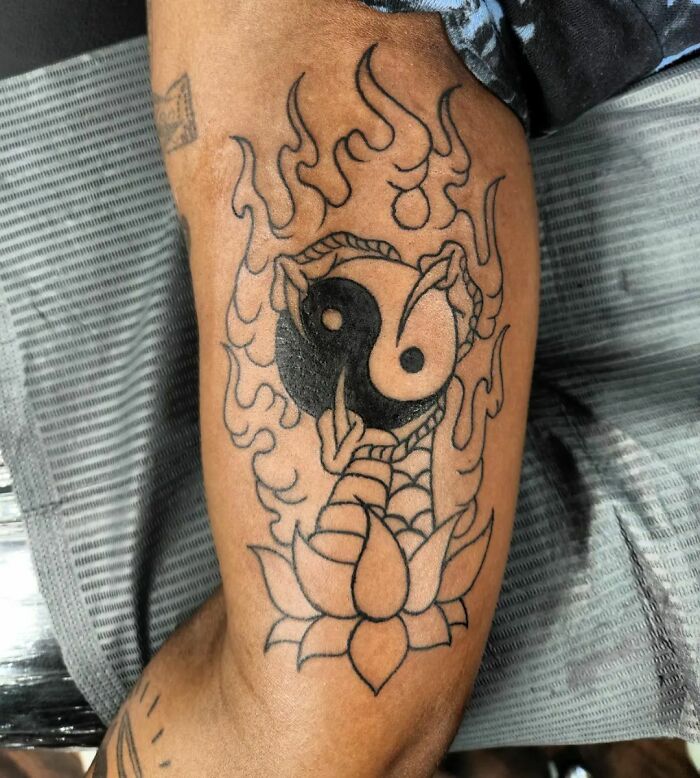 Yin Yang tattoo design with flames and lotus on an arm.