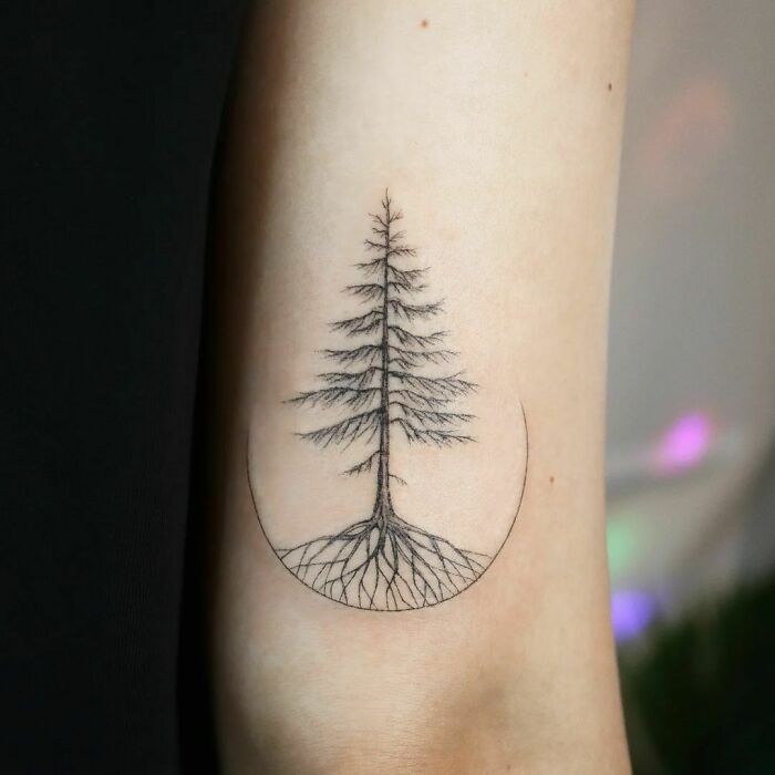 Minimalist tree tattoo design on inner elbow with roots extending in a circular pattern, highlighting dazzling elbow tattoos.