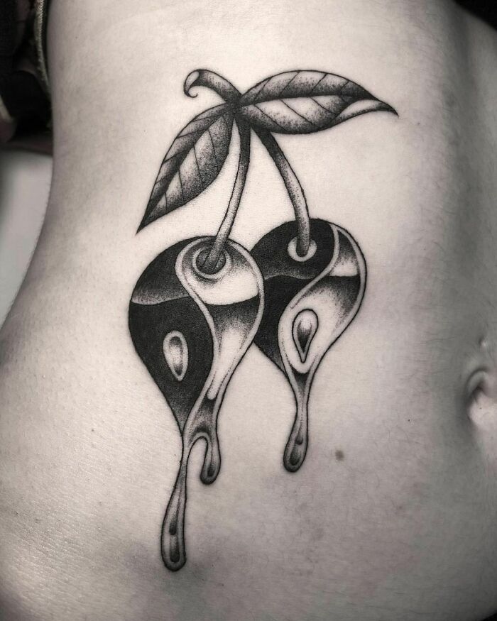 Yin Yang tattoo of stylized cherries with dripping design, symbolizing life's duality.