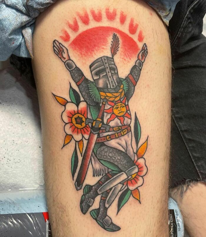 Dark Souls Video game tattoo featuring a knight with flowers and a red sun design on the leg.