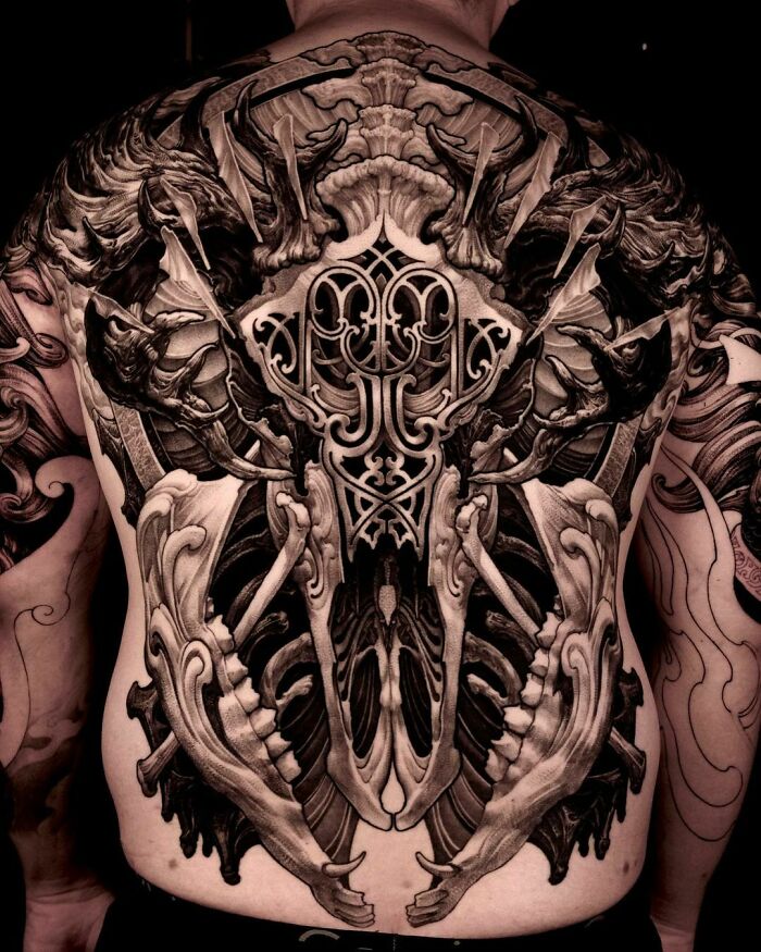 Gothic tattoo design covering a man's back, featuring intricate symmetrical patterns and dark shades.