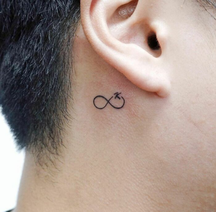 Infinity tattoo behind ear, symbolizing eternal creativity.