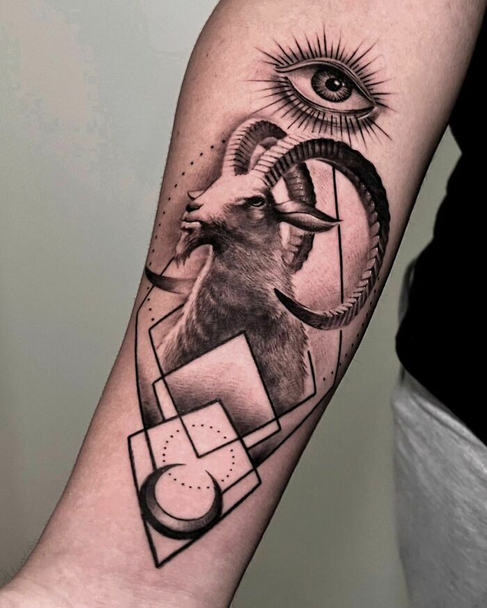 Zodiac tattoo featuring a Capricorn goat with geometric shapes and an all-seeing eye on forearm.