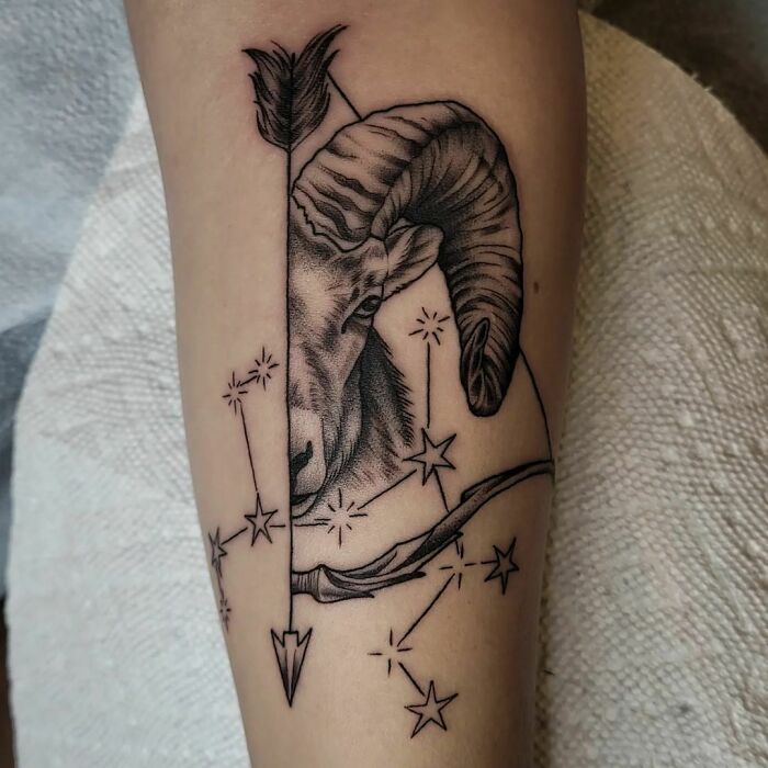Zodiac tattoo of an Aries ram with an arrow and stars on an arm.