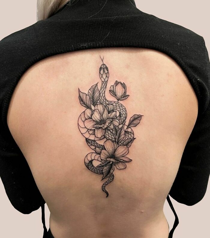 Snake tattoo design on a person's back, featuring intricate floral details.