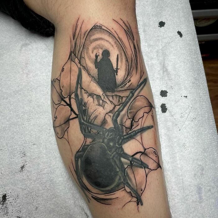 "Detailed Lord of the Rings tattoo featuring a spider and a shadowy figure on a mountain background."