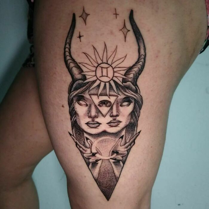 Gemini zodiac tattoo featuring dual faces, geometric shapes, stars, and horns on the upper thigh.