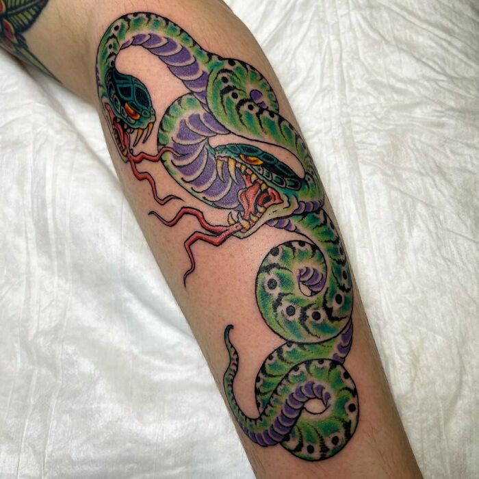 Colorful snake tattoo with green and purple shades on an arm.