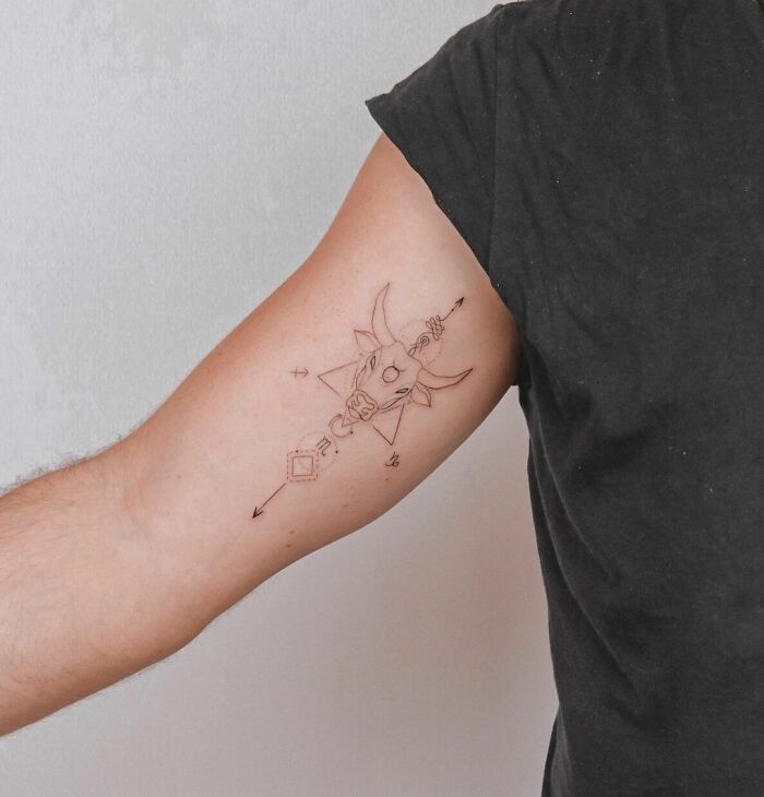 Minimalist bull zodiac tattoo on arm in black ink.