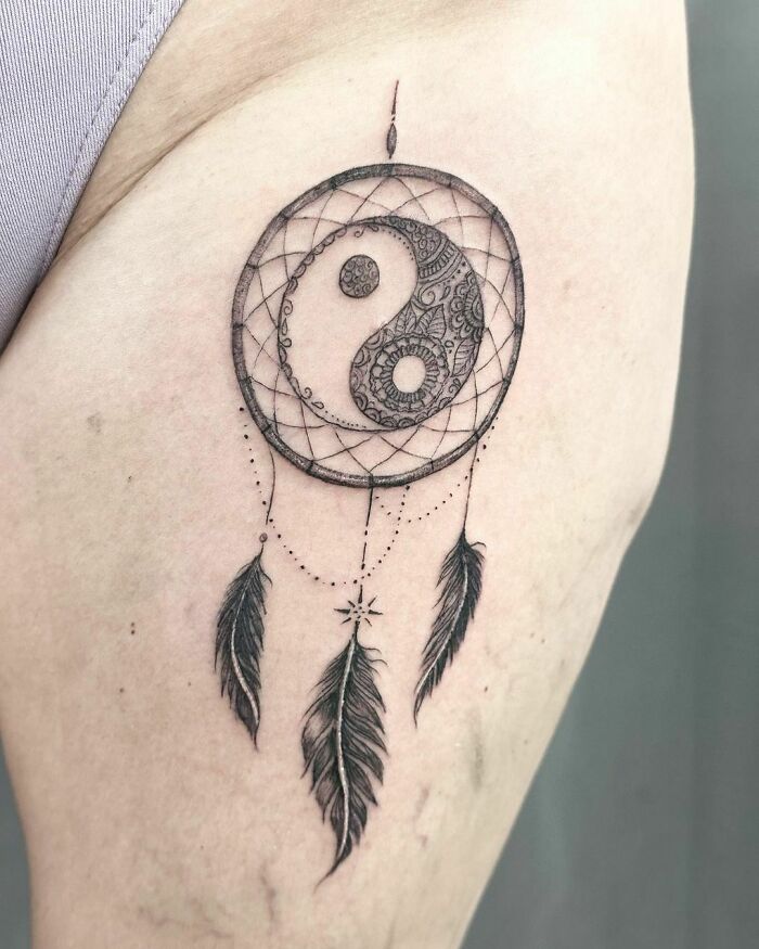 Yin Yang tattoo with detailed patterns and dreamcatcher elements on skin.