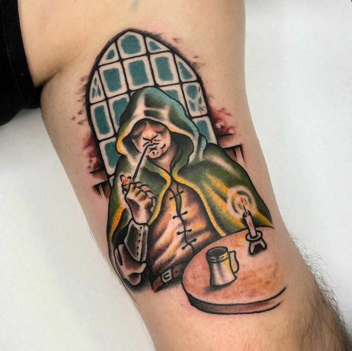 Tattoo depicting a cloaked figure from Lord of the Rings, sitting by a candle with a pipe.