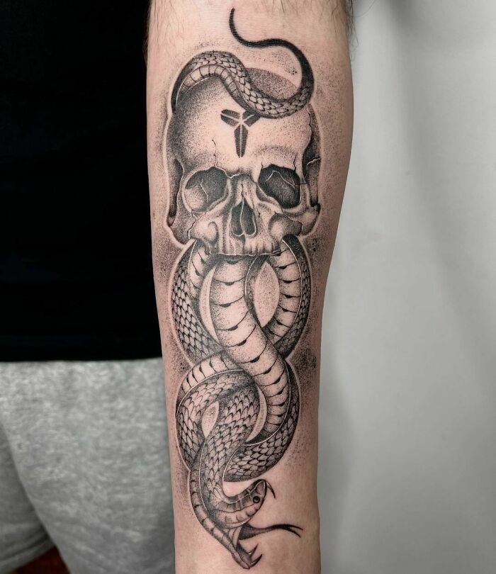 Snake tattoo intertwining with skull design on a forearm.