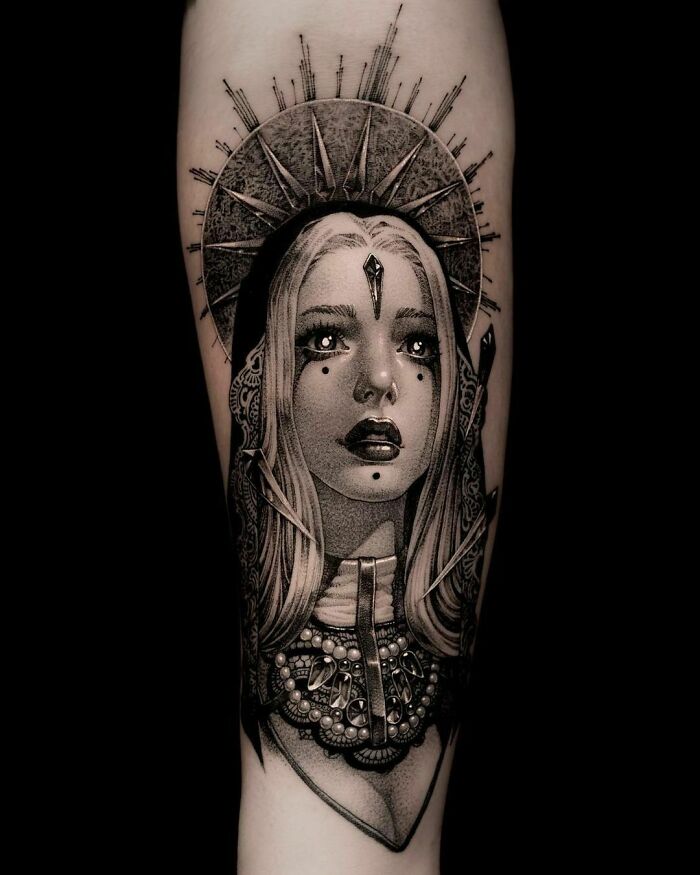Gothic tattoo featuring a woman with intricate detailing and a halo design on the forearm.