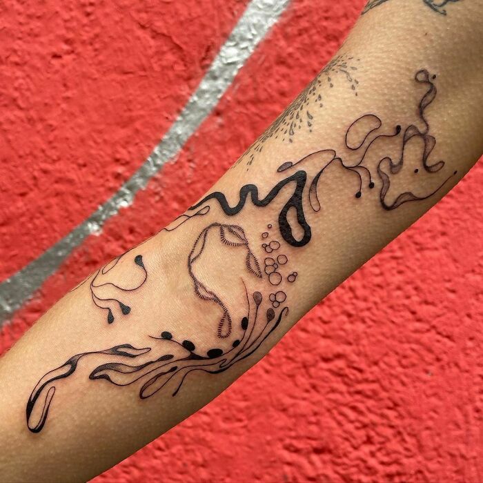 Abstract tattoo design on forearm, showcasing artistry and self-expression against a red background.